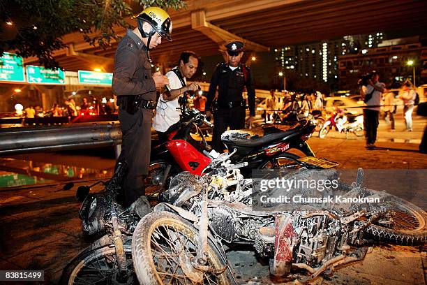 Thai policemen inspect the motorbikes that were set fire to by anti-government protesters at Vibhavadi Road on November 25, in Bangkok, Thailand....