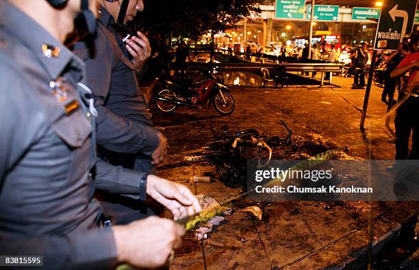 Thai policemen inspect the motorbikes that were set fire to by anti-government protesters at Vibhavadi Road on November 25, in Bangkok, Thailand....