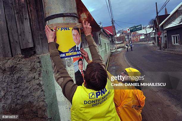 Romanian party activists fix an National Liberal Party electoral poster in Hoghiz village on November 25, 2008. Romanians are called to ballots next...