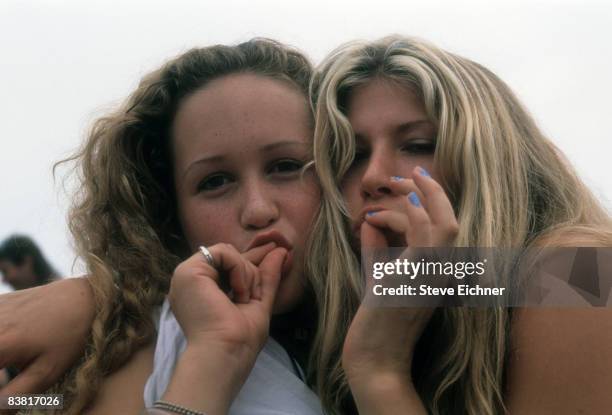 Two young concert goers at the 1994 Woodstock Music Festival mime the act of smoking marijuana, 1994. Saugerties New York.