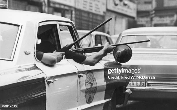 View of the arms of police officers as they hold rifles out of the windows of a police cruiser on Springfield Avenue during the Newark riots, Newark,...