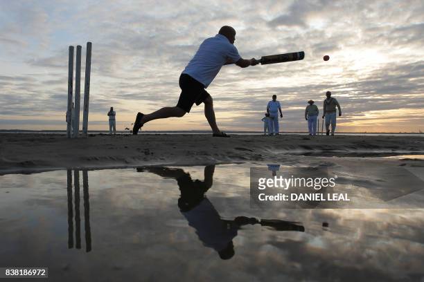 Man plays a shot as teams play an annual cricket match in the middle of The Solent, on the Brambles sandbank which appears in the sea for a short...