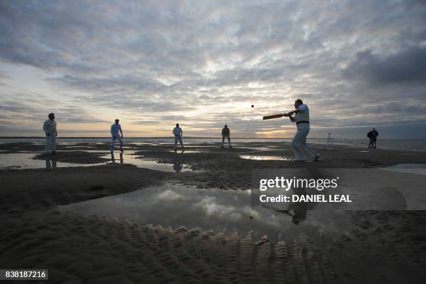 Man plays a shot as teams play an annual cricket match in the middle of The Solent, on the Brambles sandbank which appears in the sea for a short...