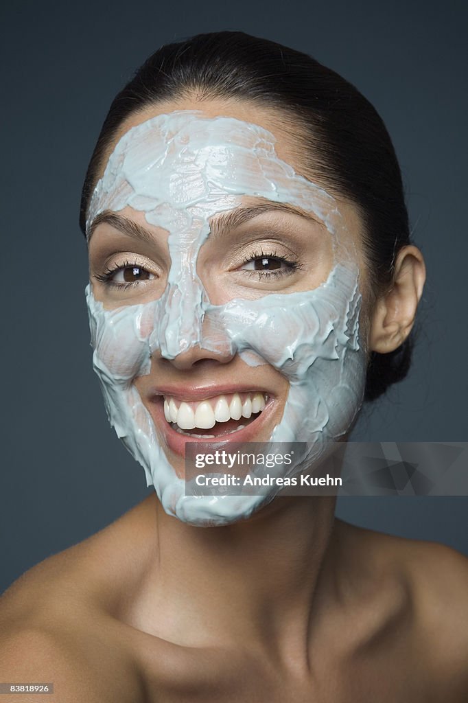 Smiling woman with blue facial mask, close up.