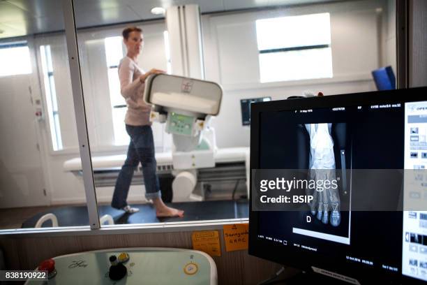 Radiology center, France, technician carries out a foot x-ray on a patient who had an operation on a hallux valgus.