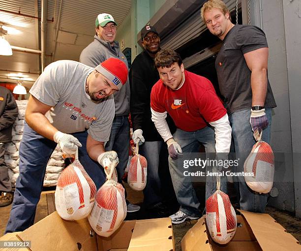 Giant Football players Grey Ruegamer, David Diehl, Kevin Boothe, Chris Snee and Adam Koets pose for a photo while they load trucks with turkeys and...