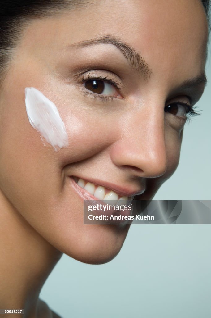 Woman with lotion on cheek, close up.