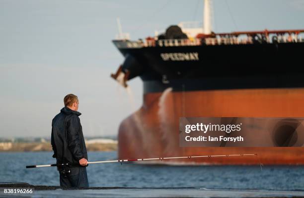 Fisherman stands on the end of the breakwater as a tanker enters the mouth of the River Tees at South Gare on August 24, 2017 in Redcar, England. The...