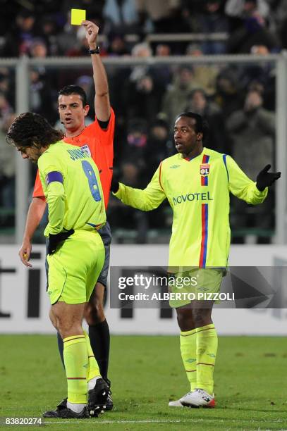 Hungarian referee Viktor Kassai shows a yellow card to Lyon's Brazilian midfielder Pernambucano Juninho during their Champions League group F...