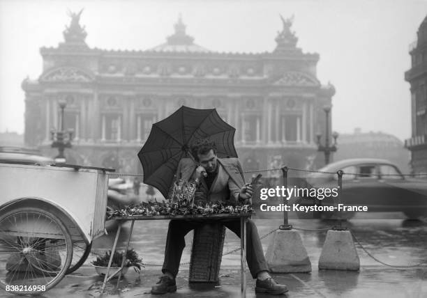 Vendeur de muguet sous la pluie Pace de l'Opéra à Paris, France en 1951.