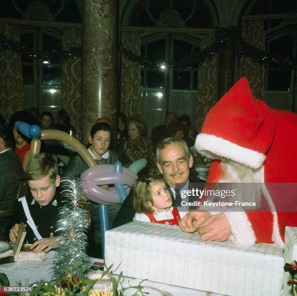 La princesse Stéphanie en compagnie de son père le prince Rainier découvre le cadeau que lui offre le Père Noël, à gauche le prince Albert ouvre son...