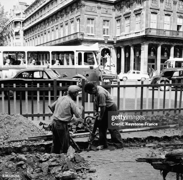 Place du Théâtre-Français, les ouvriers creusent au marteau-piqueur une tranchée pour installer de nouvelles canalisations électiques, à Paris,...