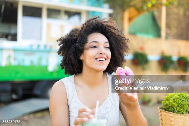donna sorridente che mangia ciambella - eating donuts foto e immagini stock