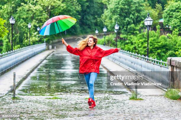 bella ragazza con ombrello che balla sotto la pioggia - vestito multicolore foto e immagini stock
