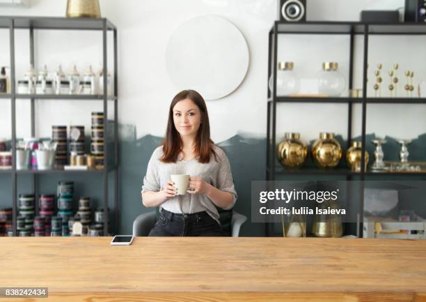 woman with mug in shop behind counter - inside coffe store stock-fotos und bilder