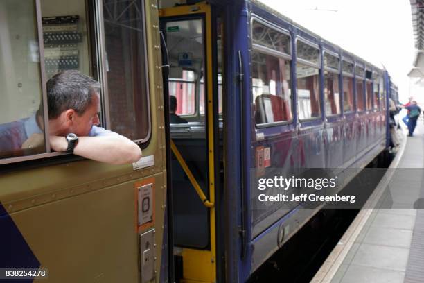 Train engineer watches boarding passengers at Deansgate Station.