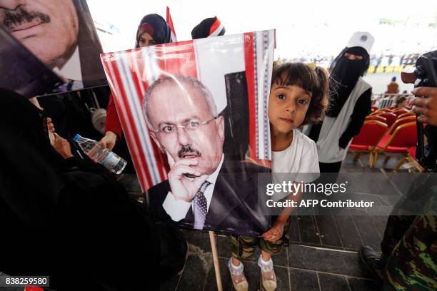 Yemeni girl holds a portrait of Yemen's ex-president Ali Abdullah Saleh, as his supporters attend a rally marking 35 years since the founding of the...