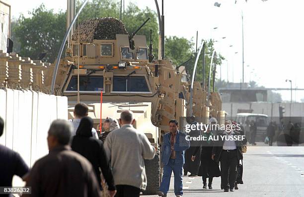 Iraqis walk past military vehicles as they arrive at one of the entrances to the fortified 'Green Zone' which houses the Iraqi parliament, several...