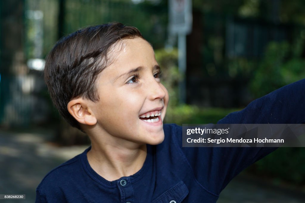 Portrait of a young Hispanic boy smiling and looking away from the camera