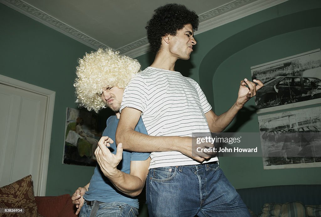 Two men playing air guitar