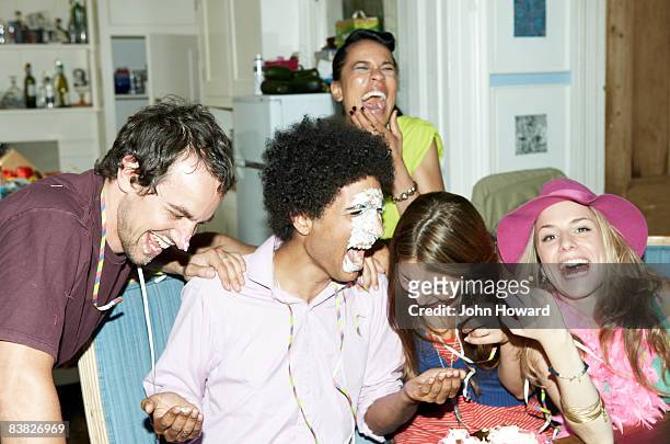 man with icing on his face laughing with friends - concepts & topics stock pictures, royalty-free photos & images
