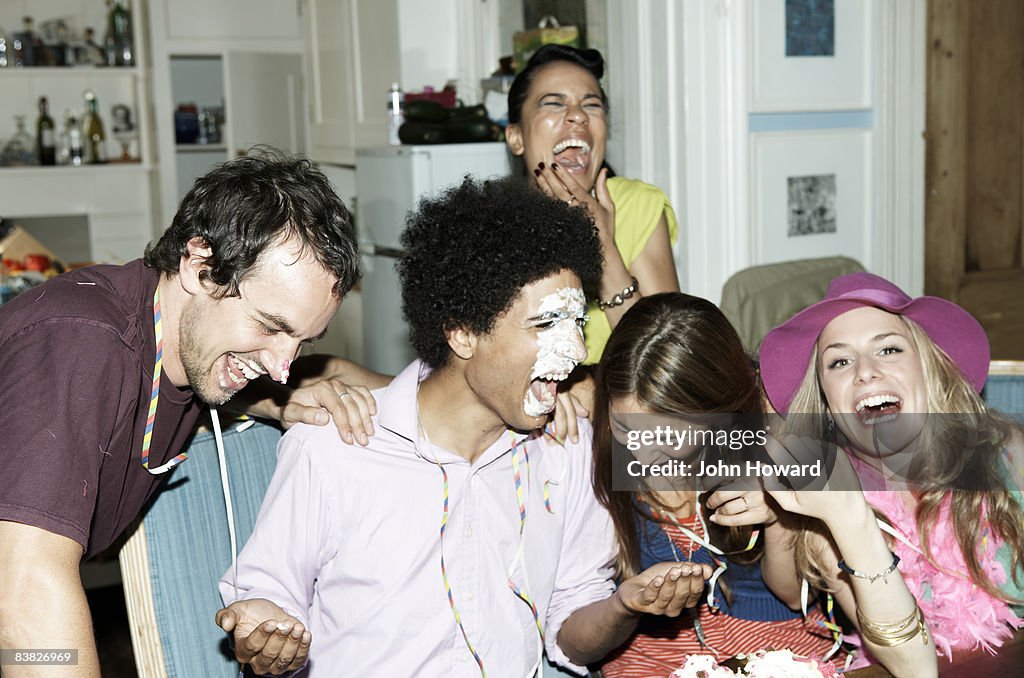 Man with icing on his face laughing with friends
