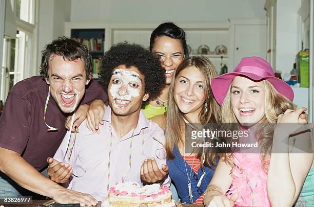 man with icing on his face posing with friends - absurd birthday stock pictures, royalty-free photos & images