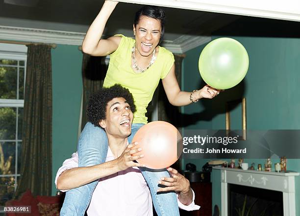 man carrying woman on shoulders putting up balloon - couple party bildbanksfoton och bilder