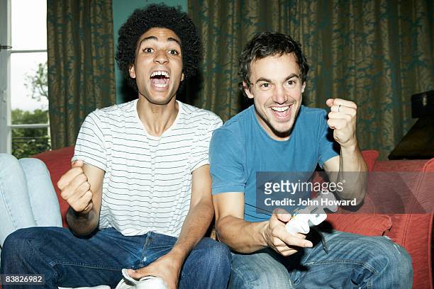 friends playing video game - playing sofa stockfoto's en -beelden