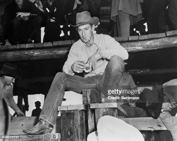 Bill Linderman, 1947 All-Around Champion Cowboy and co-producer of the Bucking Bronco Auction sale takes time out for a smoke while bossing the cute...