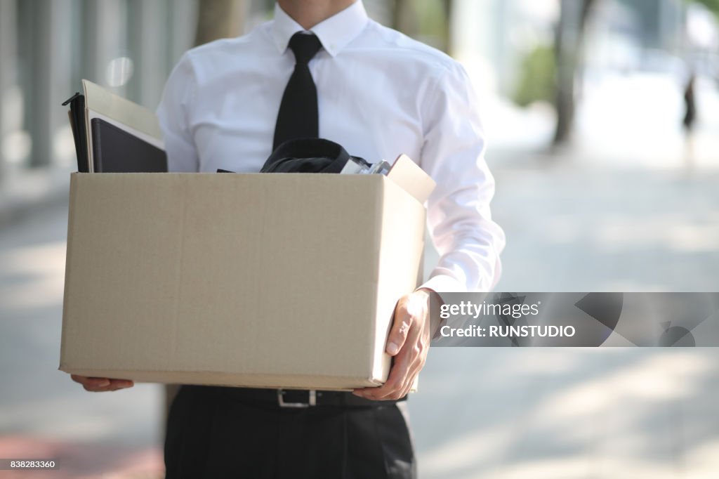 Close-up Of Unemployed Businessperson Carrying Cardboard Box