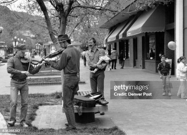 Feature art Boulder, Pearl St. Mall L to R Playing there violins are Tom Coleman and Jim Remington Watching holding his Baby is Mr.Jeff Haemer and...