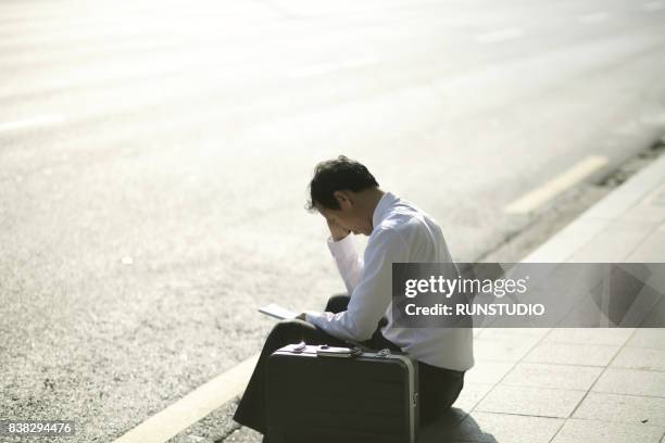 fired businessman reading the notice of job termination - rinnsteinkante stock-fotos und bilder