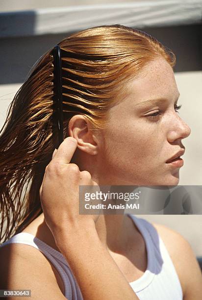 young woman combing her hair, outdoors - haare stock-fotos und bilder