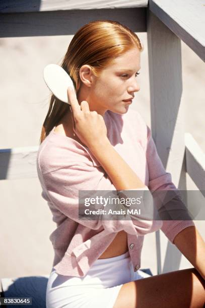 young woman sitting on a balcony, brushing her hair - hair imagens e fotografias de stock