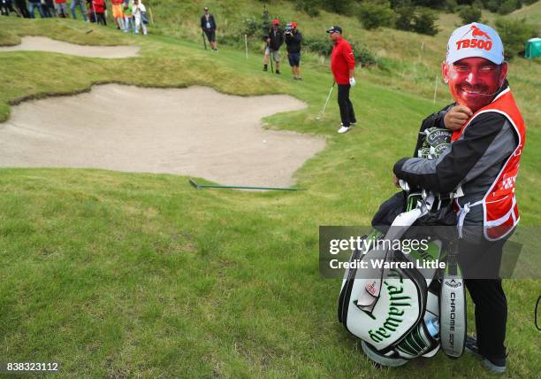 Caddie for Thomas Bjorn of Denmark marks his 500th European Tour appearance by doning look a like face mask on the 16th green during the first round...