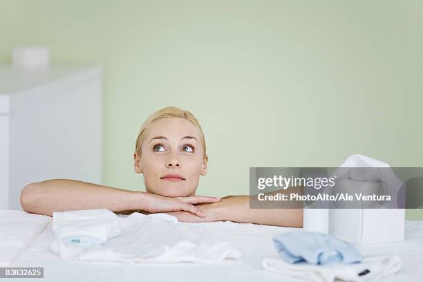 Woman In Nursery Resting Head On Arms Looking Up Smiling High-Res Stock Photo