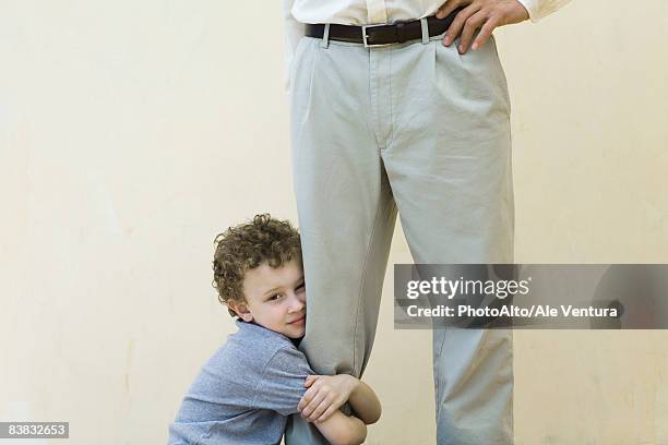 boy clinging to his father's leg, looking at camera, cropped view - weakness stock pictures, royalty-free photos & images