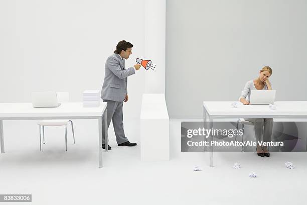 supervisor shouting at employee with megaphone, woman sitting with laptop, surrounded by crumpled paper - bullying stock pictures, royalty-free photos & images