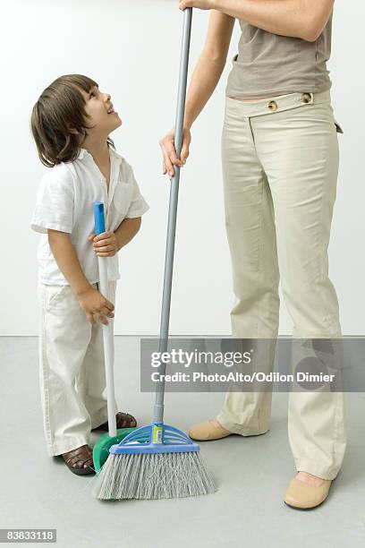 little boy helping his mother sweep the floor, cropped view - barre class fotografías e imágenes de stock