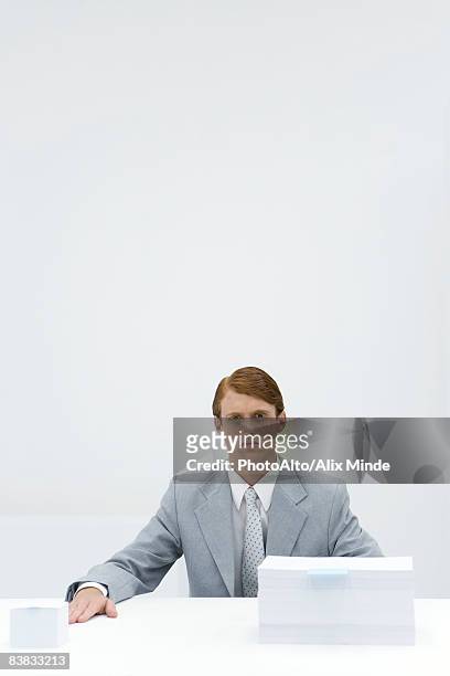businessman sitting at table with two different sized stacks of paper - asymmetry stock pictures, royalty-free photos & images