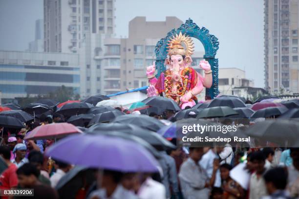 people with umbrella gathered to watch ganesh idol immersion - ganesh chaturthi stock pictures, royalty-free photos & images