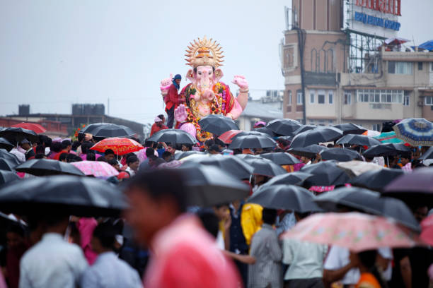 people with umbrella gathered to watch ganesh idol immersion - ganesh chaturthi stock pictures, royalty-free photos & images