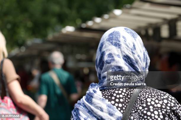 a muslim woman is buying in a market - velo foto e immagini stock