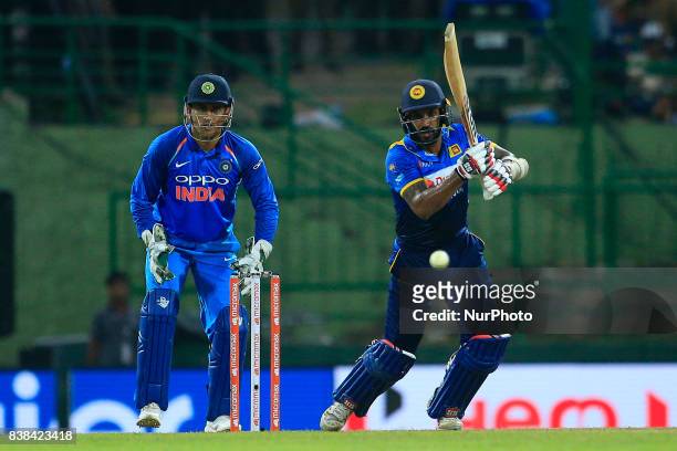 Sri Lankan cricketer Chamara Kapugedera plays a shot as Indian wicket keeper Mahendra Singh Dhoni looks on during the 2nd One Day International...