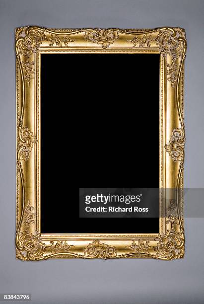 an ornate gold frame on a grey-blue wall - photo frame stock pictures, royalty-free photos & images