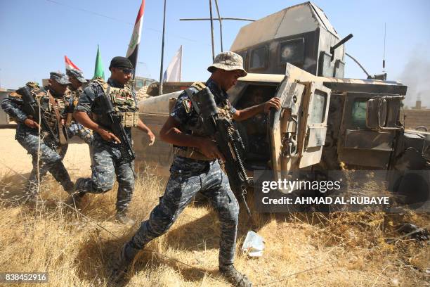 Members of the Iraqi forces, backed by the Hashed al-Shaabi , advance through Tal Afar's al-Wahda district during an operation to retake the Iraqi...