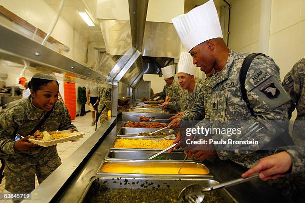 Army senior officers serve up the food to military personnel in the dining hall to celebrate Thanksgiving Day at the US military forward operating...