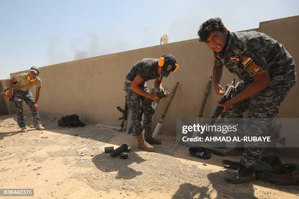 Members of the Iraqi forces take position on a roof as troops, backed by the Hashed al-Shaabi , advance through Tal Afar's al-Wahda district during...