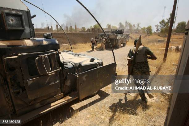 Members of the Iraqi forces, backed by the Hashed al-Shaabi , advance through Tal Afar's al-Wahda district during an operation to retake the Iraqi...